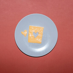 Cheese with heart shape on a plate creative food concept.