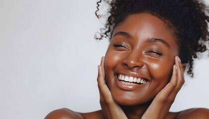 A beautiful woman with radiant skin smiles and touches her face on a white background