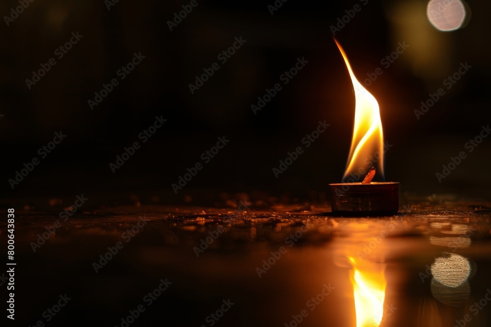 Aufkleber a singular candle light casts a warm glow and reflection on a wet surface, invoking comfort and inti