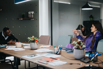 A modern office environment where a diverse group of business professionals discuss work. The setting is vibrant and professional, showcasing teamwork and communication.