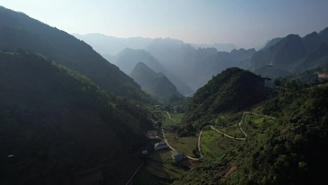Spectacular aerial view of a valley enveloped by mountains and lush vegetation Ha Giang Loop Vietnam Asia 4K drone view