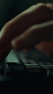 Vertical monitor. A focused hacker programmer works in the dark, his fingers easily sliding over the keys of a laptop. Work outside the office from the comfort of your own home