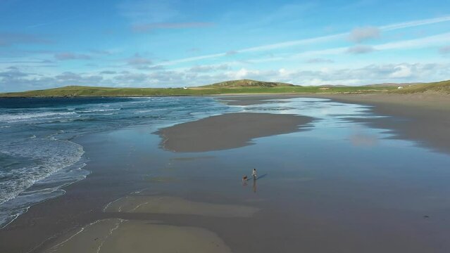 Machir Bay Beach at Kilchoman on Inner Hebrides island of Islay, Scotland. Aerial video looking north. Woman walking dog