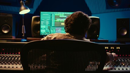 Audio expert does mixing and mastering on tracks using digital editing software in studio,...