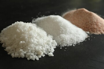 Different types of organic salt on black table, closeup