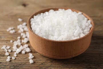 Natural salt and bowl on wooden table, closeup