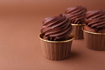 Delicious chocolate cupcakes on brown background, closeup. Space for text