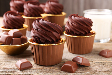 Delicious cupcakes and chocolate pieces on wooden table, closeup