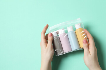 Cosmetic travel kit. Woman holding plastic bag with small bottles of personal care products against...