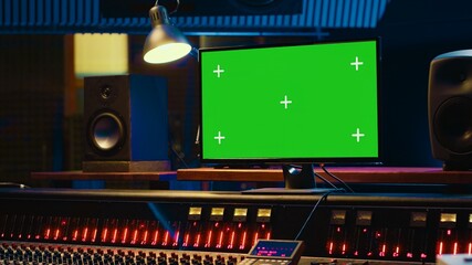 Empty professional recording studio control room with greenscreen on display, editing and processing tracks. Motorized faders, buttons and sliders operated for mix and master techniques. Camera A.