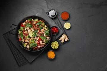 Stir-fry. Tasty noodles with meat in wok and ingredients on grey textured table, flat lay. Space for text