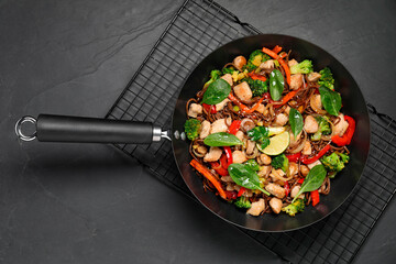 Stir-fry. Tasty noodles with meat and vegetables in wok on grey textured table, top view