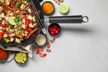 Stir-fry. Tasty noodles with meat in wok, chopsticks and ingredients on grey textured table, flat...