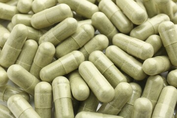 Light green vitamin capsules as background, top view