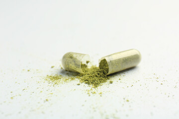 Broken light green vitamin capsule on white background, closeup