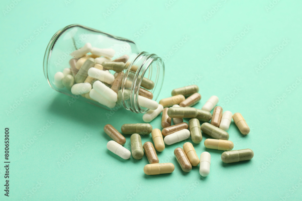 Poster Vitamin pills and bottle on mint color background, closeup