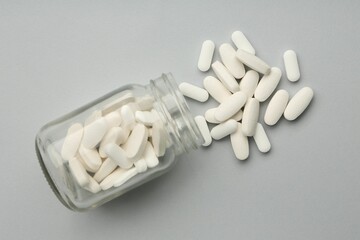 Vitamin pills and bottle on grey background, top view