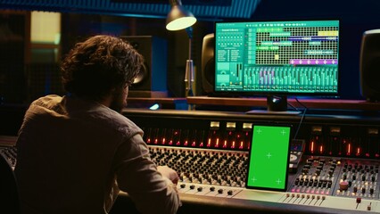 Professional audio expert mixing and mastering tracks in music production studio, pushing buttons...