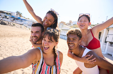 Group of cheerful diverse young gen z friends taking a selfie on the beach, smiling and having fun...