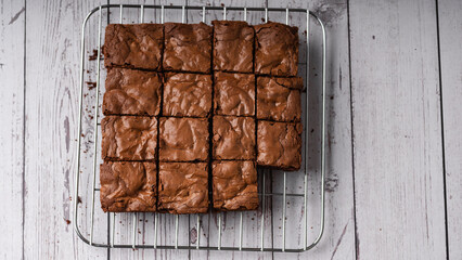 Chocolate brownies placed over a cooling rack on a wooden background. Selective focus.