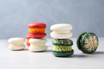 Different decorated Christmas macarons on white table, closeup