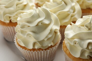 Tasty vanilla cupcakes with cream on plate, closeup