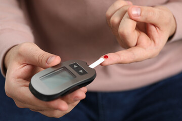 Diabetes test. Man checking blood sugar level with glucometer, closeup