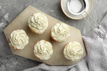 Obraz na płótnie Canvas Tasty cupcakes with vanilla cream on grey table, top view