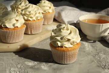 Tasty cupcakes with vanilla cream on grey table, closeup