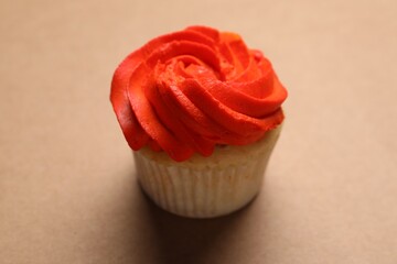 Delicious cupcake with bright cream on brown background, closeup