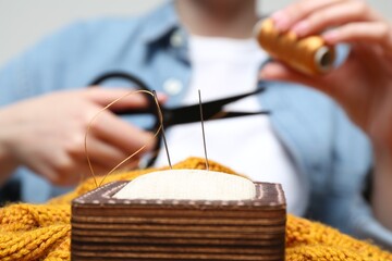 Woman sewing sweater, focus on pin cushion