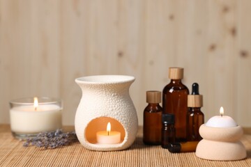 Different aromatherapy products and burning candles on table