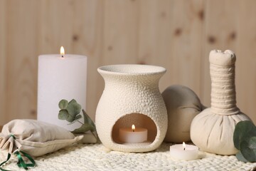 Different aromatherapy products, burning candles and eucalyptus leaves on table