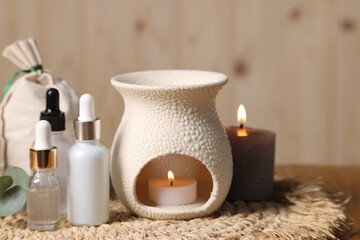 Different aromatherapy products and burning candles on table, closeup