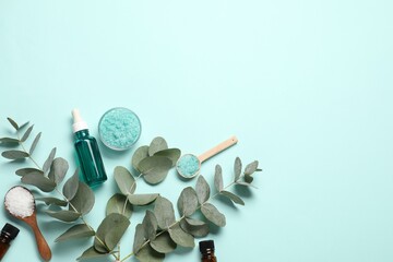 Aromatherapy products. Bottles of essential oil, sea salt and eucalyptus branches on light blue...