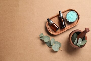 Aromatherapy products. Bottles of essential oil, sea salt, eucalyptus leaves and mortar on brown...