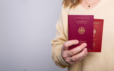 Close up of a woman in yellow sweater holding a German and a Russian passport