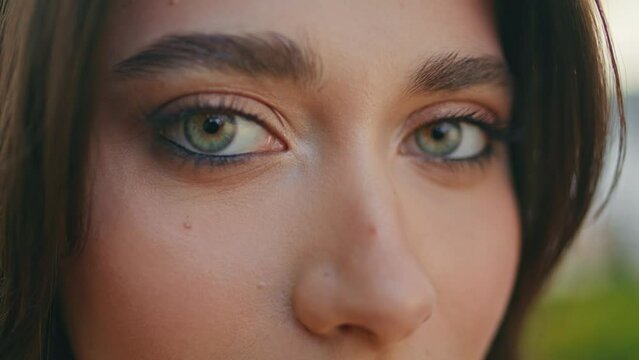 Closeup brunette eyes looking camera at nature. Green-eyed woman face portrait