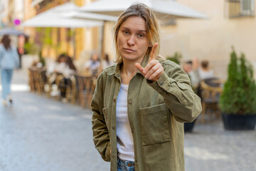 Obraz premium Displeased upset woman reacting to unpleasant awful idea, dissatisfied with bad quality shake head No, dismiss proposition, don't like proposal outdoors. Caucasian girl tourist standing on city street