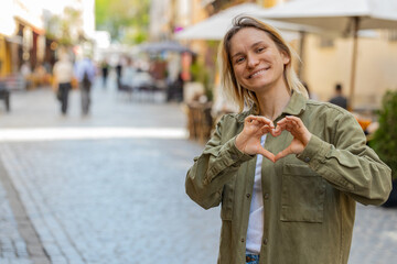 I love you. Young woman makes symbol of love, showing heart sign to camera, express romantic...