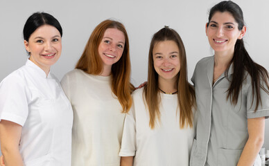 Group portrait of cosmetologists in uniform standing together and looking at camera. Female dermatologists smiling at camera in beauty clinic.
