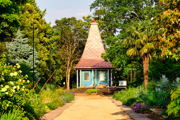A sunny view of a pointed-roof cottage or hut at the botanical garden JC Raulston Arboretum in...