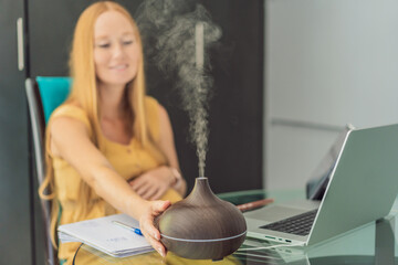 Expectant woman enhances work environment, using an aroma diffuser for a soothing atmosphere during...