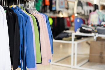 Colorful basic shirts hanging on stand in big clothing store with large assortment