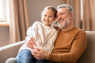 Elderly Man and Little Girl Sitting on a Couch