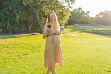 pregnant woman enjoys a cup of coffee outdoors, blending the simple pleasures of nature with the...