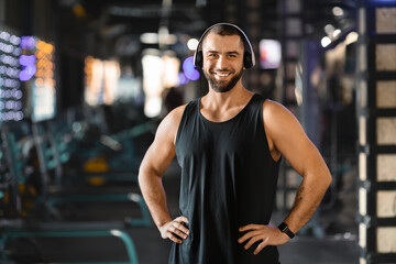 Handsome Millennial Man With Headphones Standing in Gym