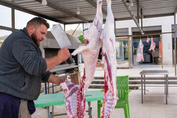 The butcher cuts the meat with knife on wooden cutting board.Close-up piece of raw meat with a...