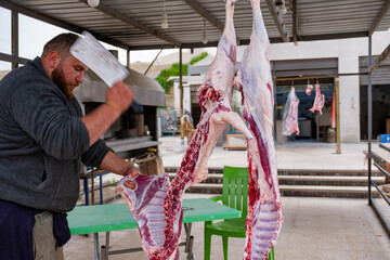 Bearded man cutting meat for poor peoples during eid in butchery