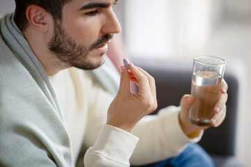 Young Man Taking Medication With a Glass of Water, Closeup